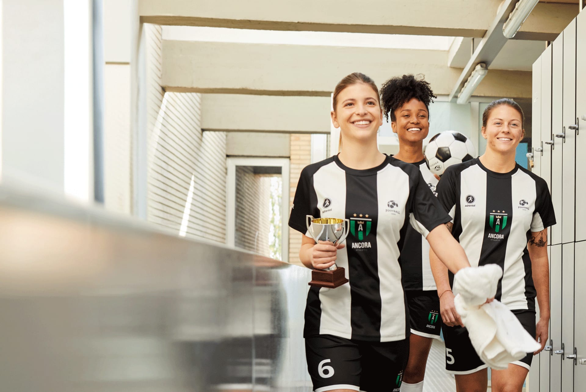 Un equipo de fútbol de mujeres luciendo una camiseta y pantalones cortos de fútbol de mujer, celebrando su victoria con un trofeo.