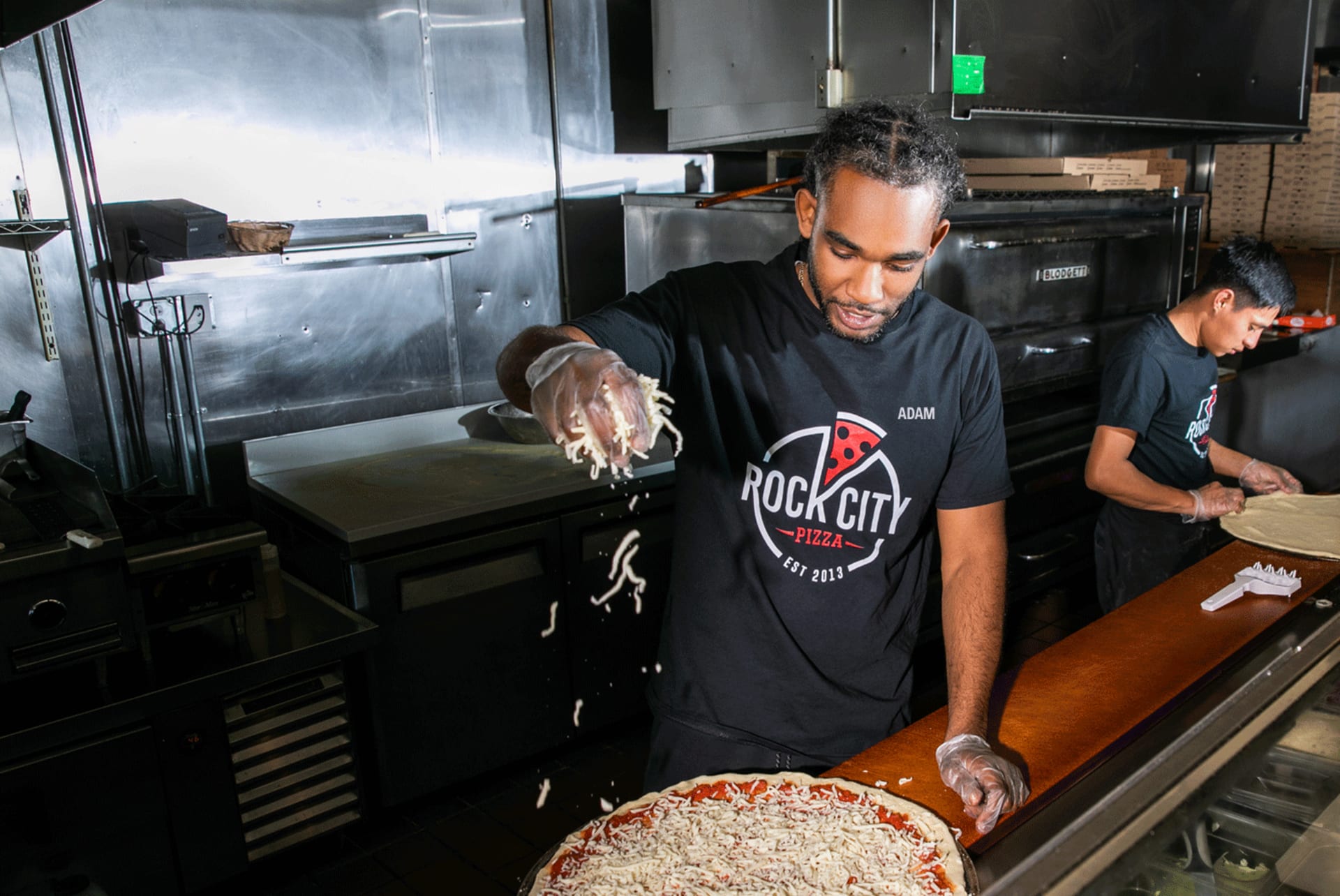 Un jeune chef cuisinier portant un authentique fait une pizza selon les règles de l’art dans son restaurant.