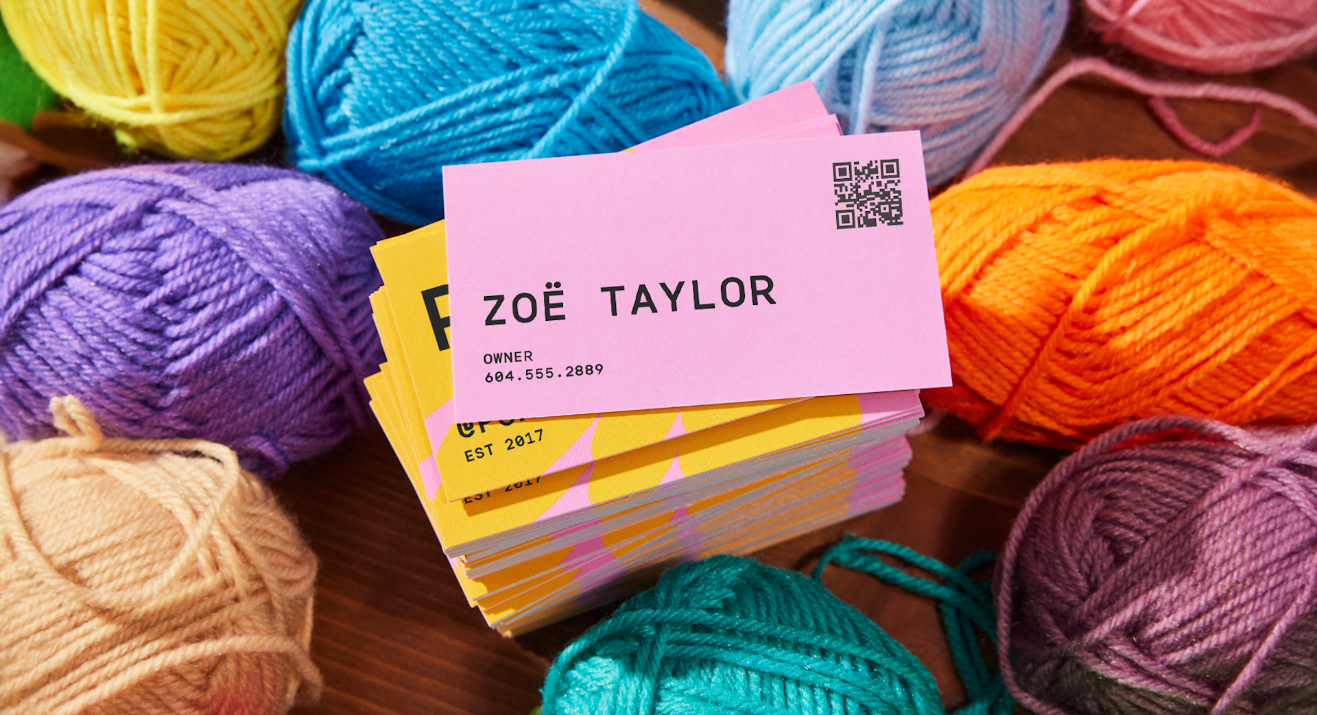 A stack of QR code business cards in a pile of colorful yarn. 
