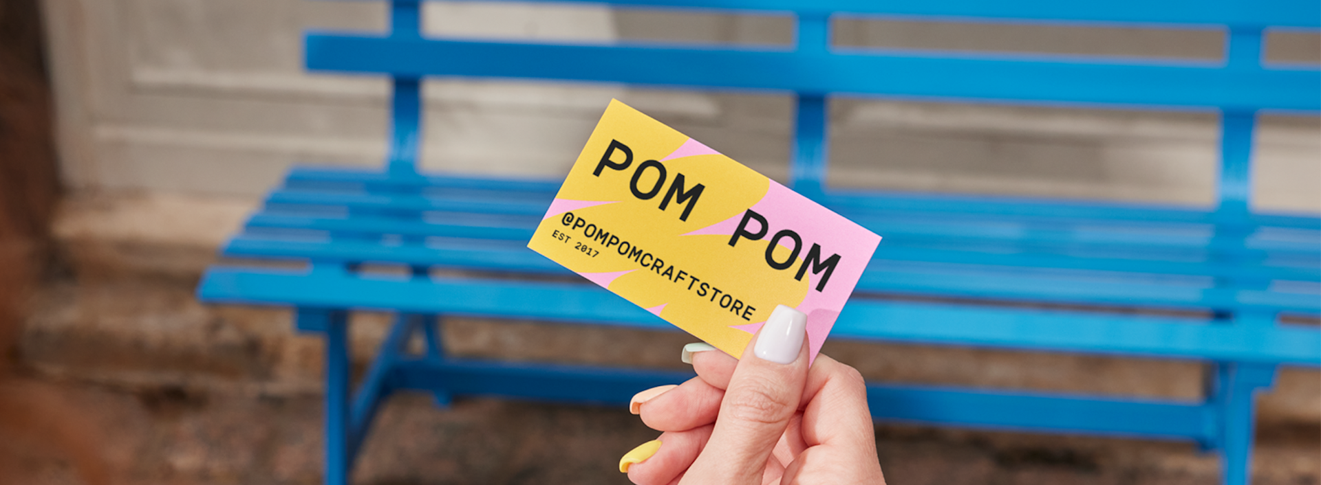 A business owner holding a business card for a crafting business.