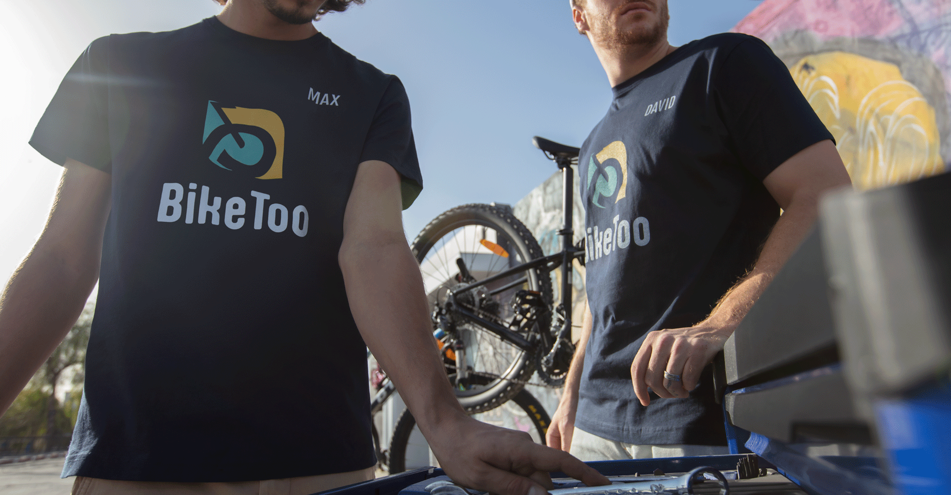 Two employees wearing navy T-shirts promoting a bike shop business.