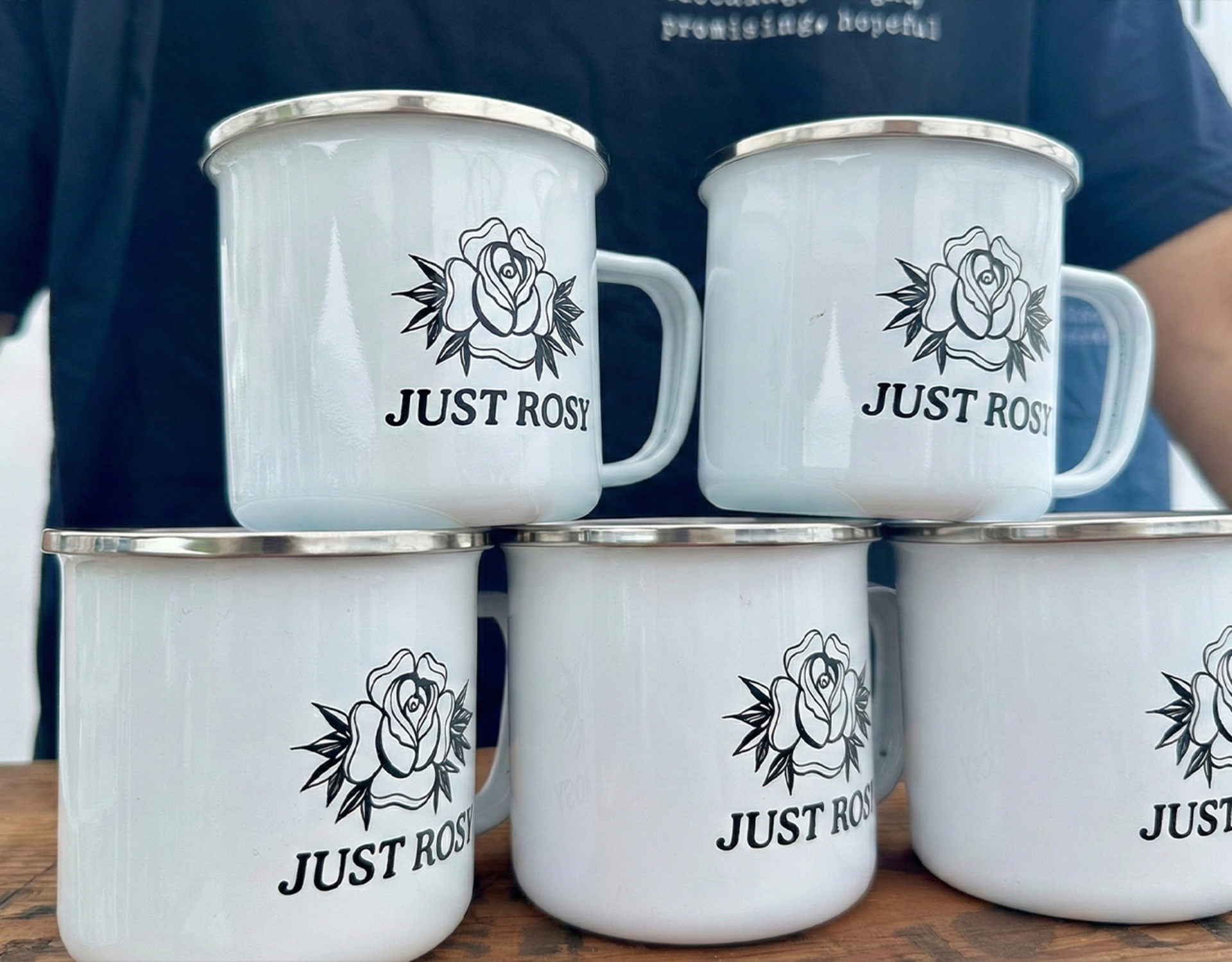 A group of personalized campfire-style enamel mugs arranged on a table, branded with the ambassador’s business name.