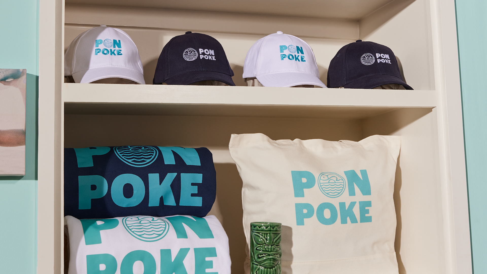 Gorras, sudaderas y bolsas personalizadas en un estante.