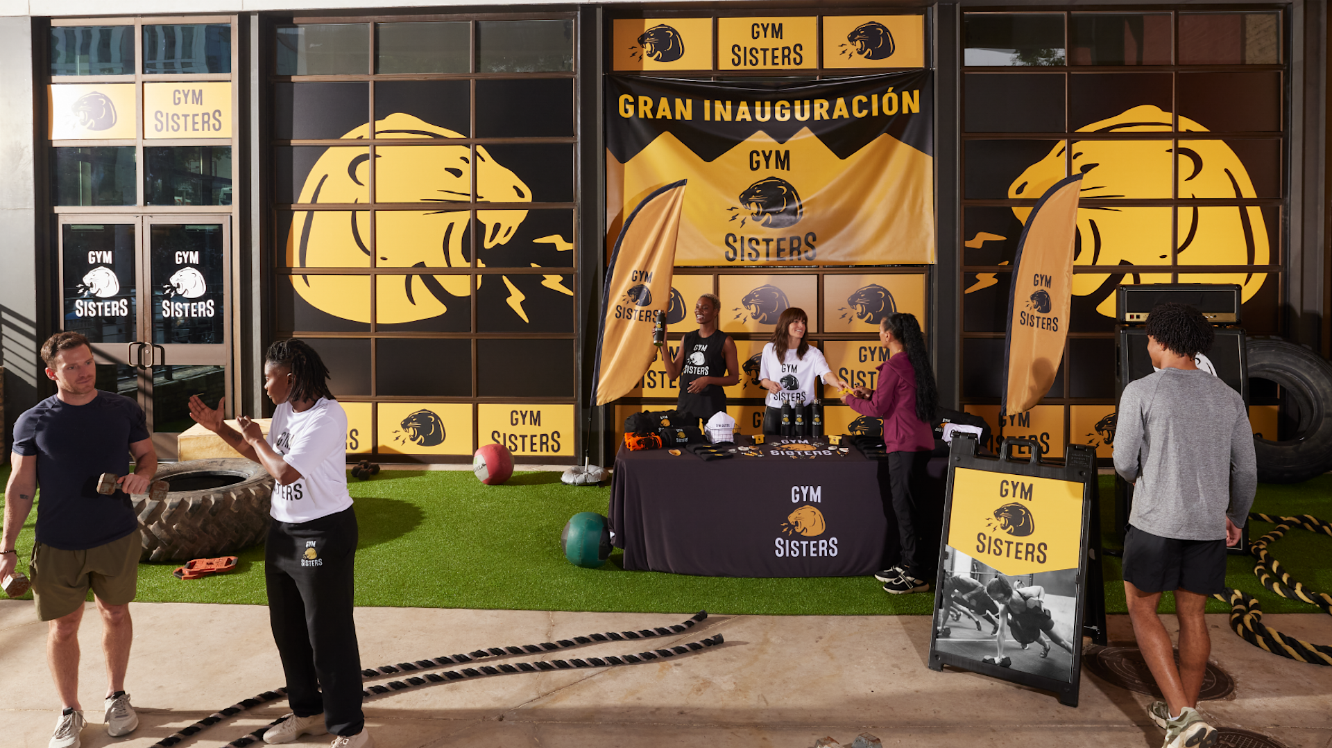 Un stand en un mercado al aire libre, con una bandera personalizada, un caballete, un mantel publicitario y una carpa. 