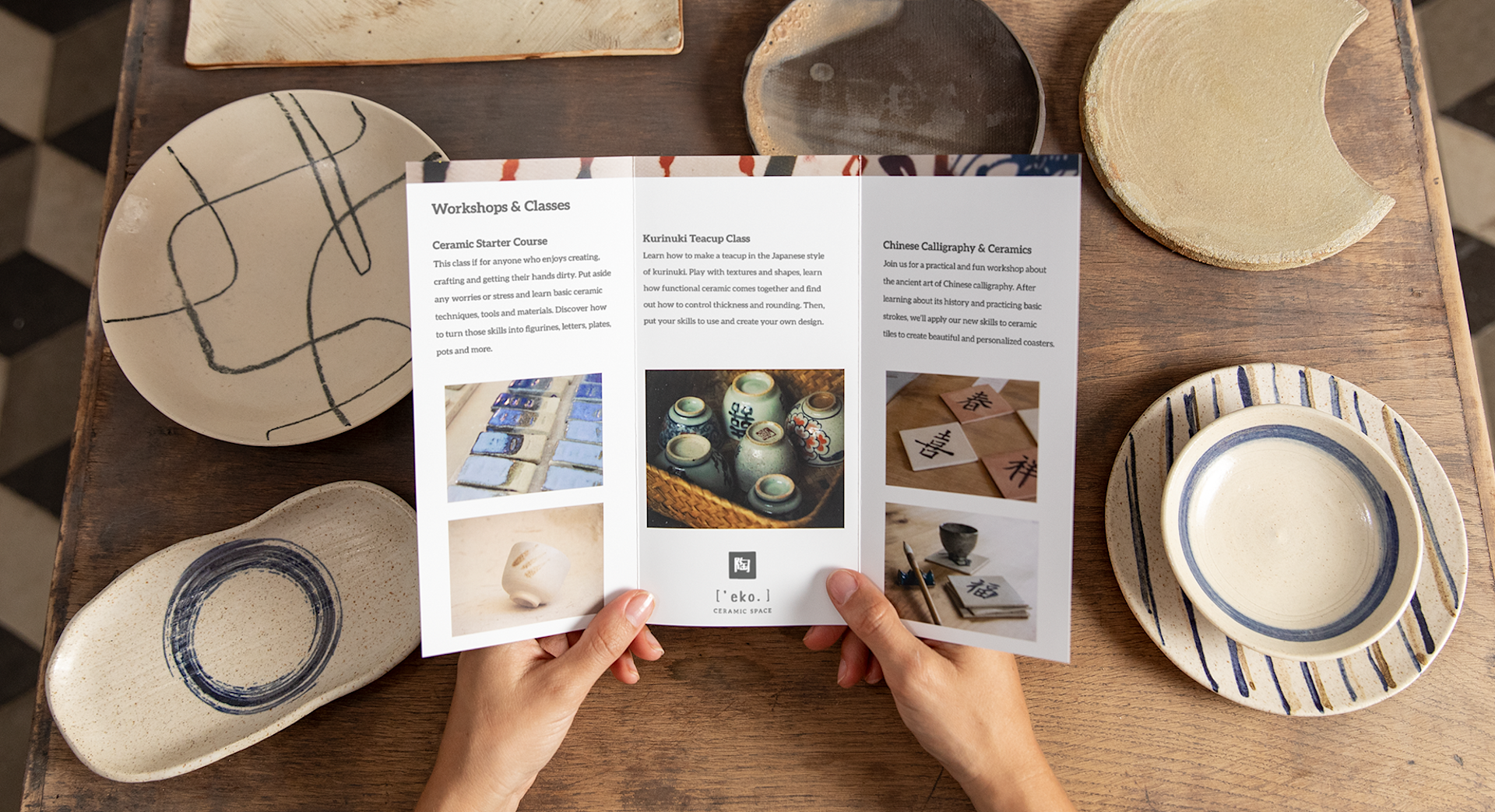 Un folleto tríptico de una empresa de arte y manualidades se vea abierto, mostrando cerámica en una mesa de madera en el fondo.