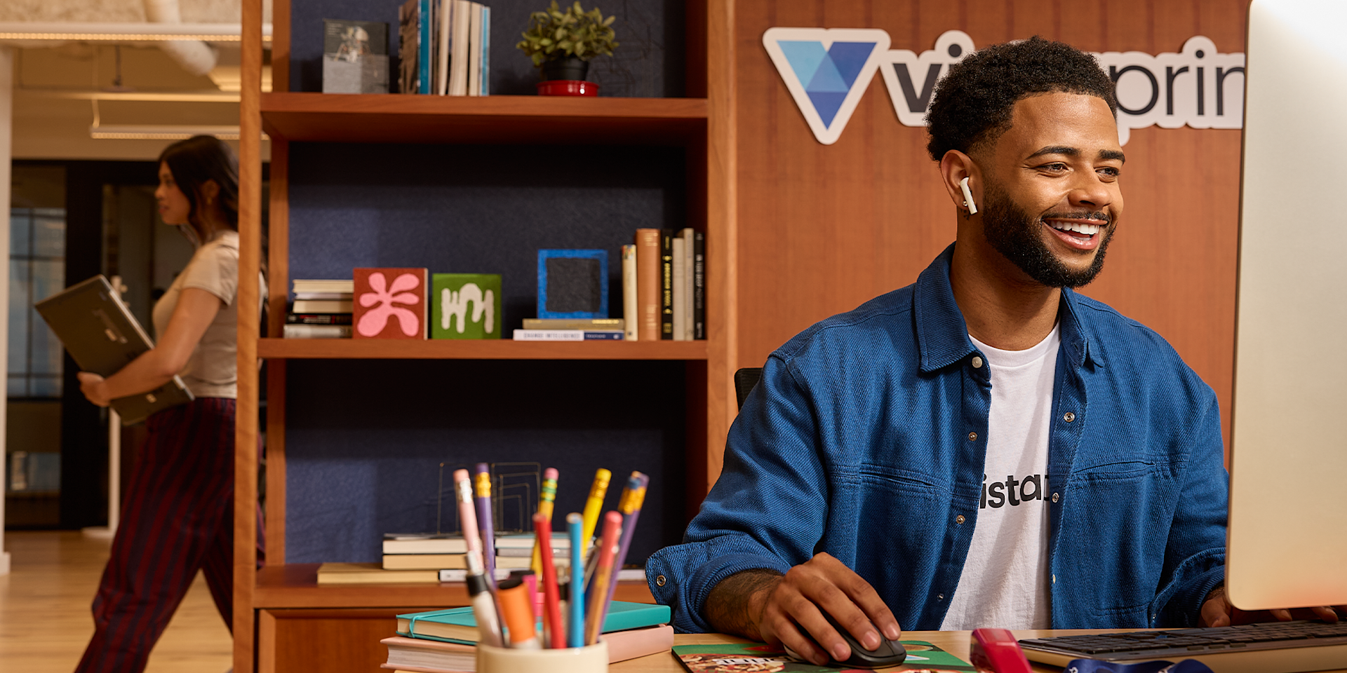 Un especialista en atención al cliente sonriente trabajando en un escritorio, ayudando a los clientes con una computadora en un ambiente de oficina acogedor.