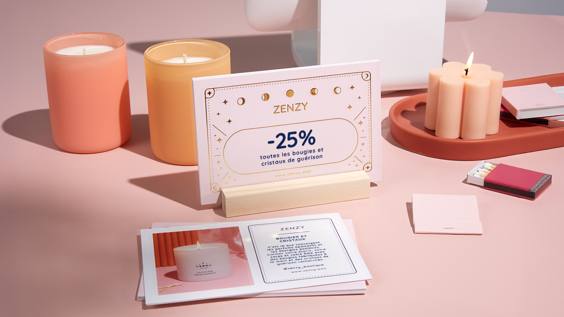 Une carte postale contenant un bon de réduction pour une boutique, présentée avec des chandelles et d’autres cartes postales.