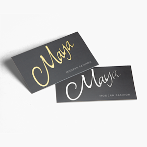 A pair of business cards, one with raised gold foil, and the other with silver foil promoting a fashion business.