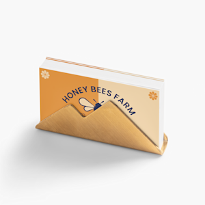 A golden business card holder featuring business cards promoting a beekeeping business.