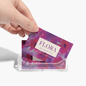 An acrylic business card holder holding business cards for a florist, with someone taking a card.