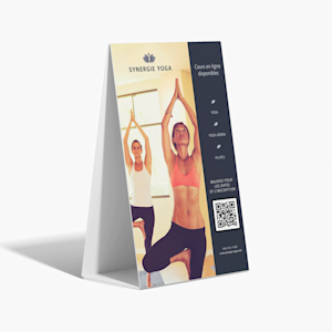 Panneau sur pieds en carton ondulé, sur fond gris, faisant la publicité d’un studio de yoga. Le graphisme contient un code QR pour aider les clients à s’inscrire aux cours.