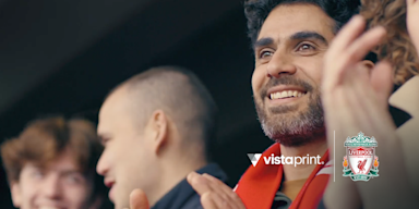 A smiling football fan wearing a red scarf.  