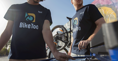 Two employees wearing navy T-shirts promoting a bike shop business.