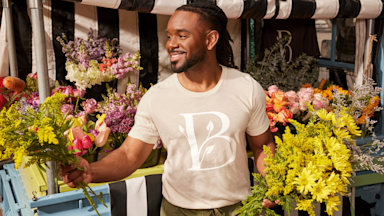 Il titolare di una rivendita di fiori che indossa una maglietta personalizzata per promuovere la sua attività.
