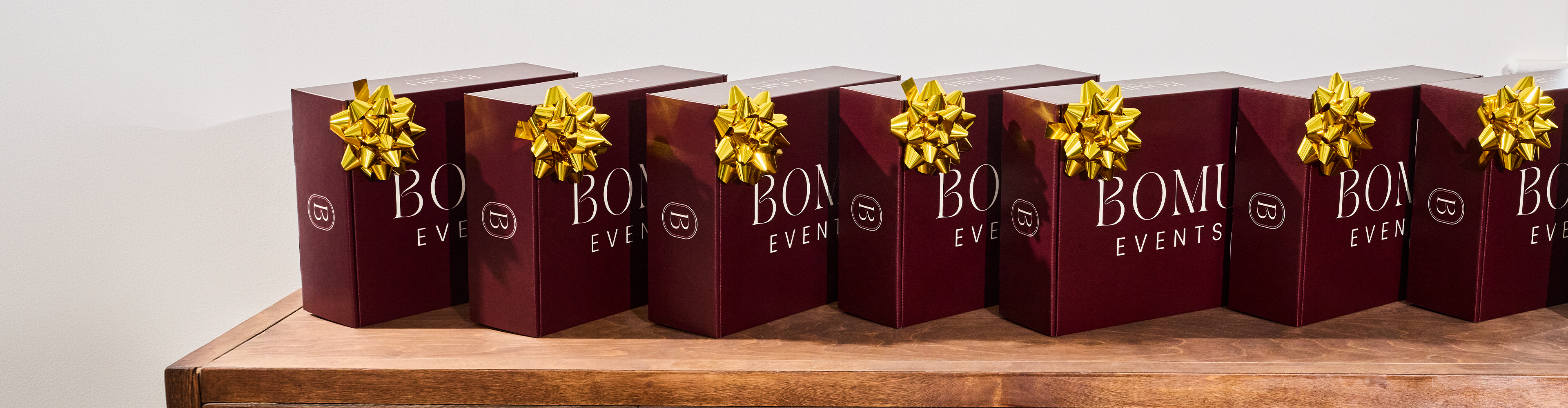 A set of holiday shipping boxes featuring a business logo, plus a gift bow. 