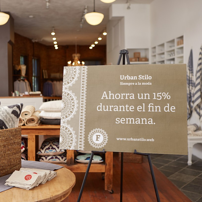 Un cartel de cartón pluma personalizado de una tienda de donas colgado en una pared. Los beneficios destacados incluyen: material grueso pero liviano, diseño y pedido en minutos, varios tamaños y formas y envío gratis en $100+. 