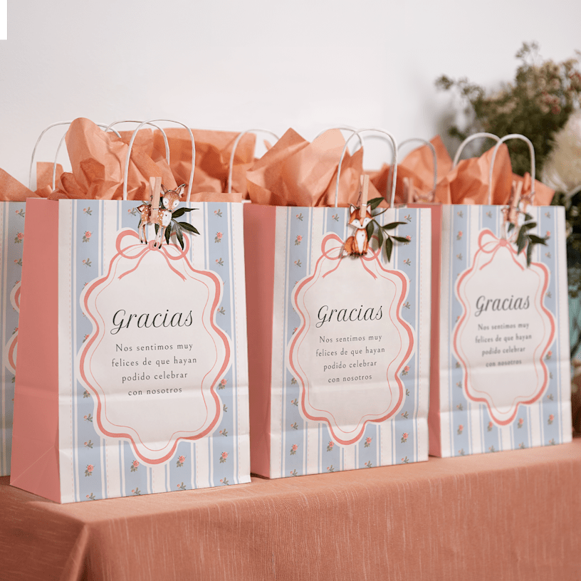 Una mesa con bolsas marrones de fiesta en un cumpleaños, decoradas con flores y cintas.