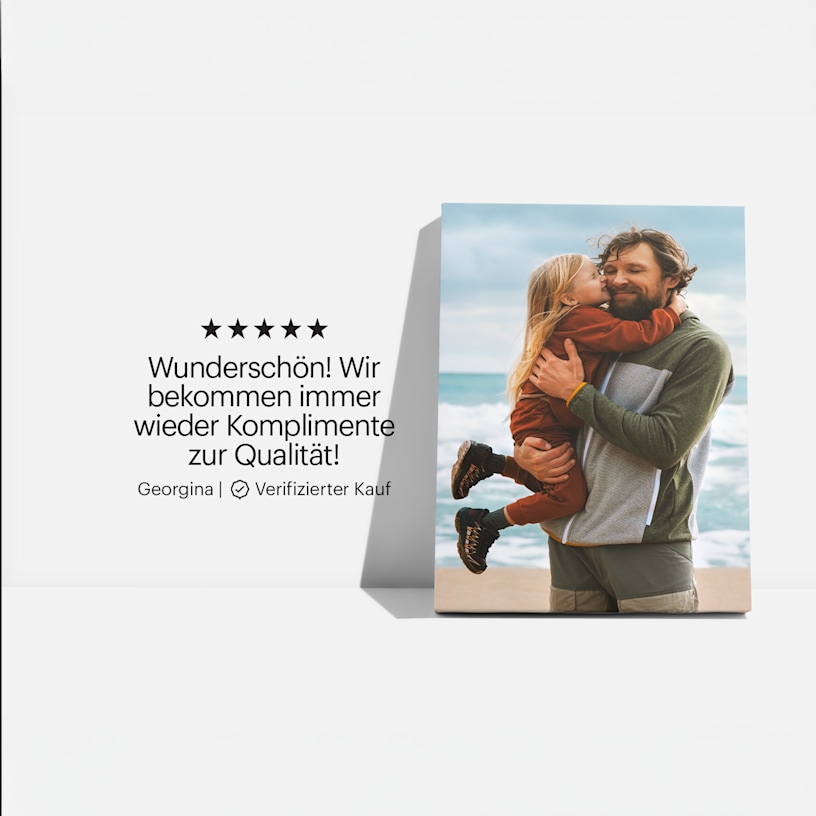 Ein Leinwanddruck mit dem Foto eines Vaters und seiner Tochter am Strand, dazu die Kundenbewertung: „Wunderschön! Wir bekommen immer wieder Komplimente zur Qualität!“