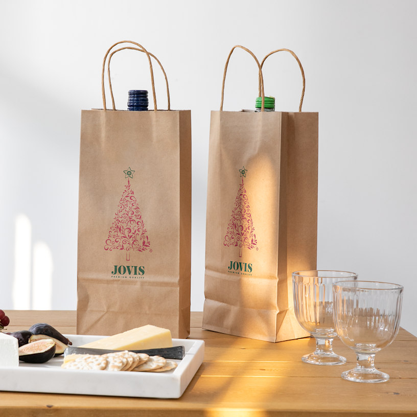 2 brown kraft wine bags with Christmas tree images on them.