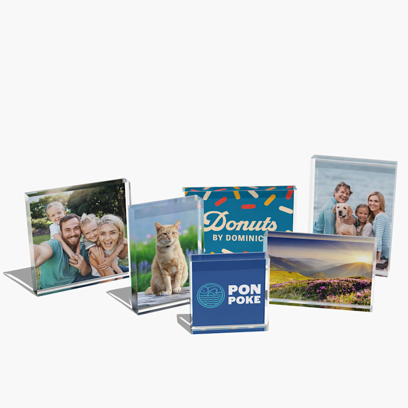 Una colección de bloques acrílicos de fotos con fotos familiares, un gato, la marca de un comercio y un paisaje escénico.