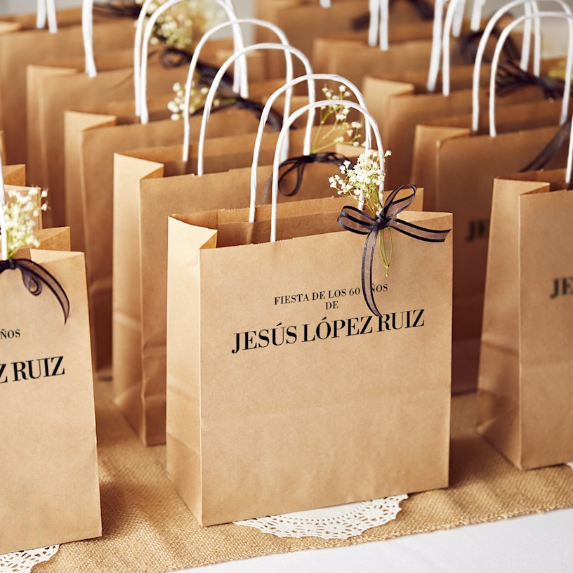 Una bolsa de papel blanca con estrellas doradas y texto celebrando un cumpleaños No. 60.