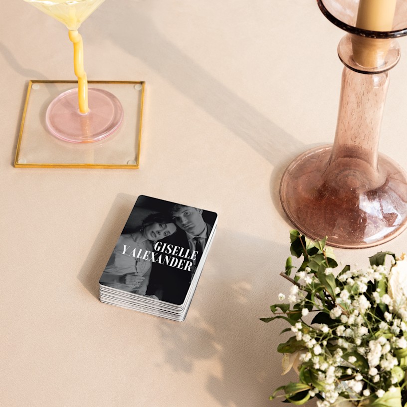 Naipes personalizados con una foto de boda, apilados en una mesa de banquete. 