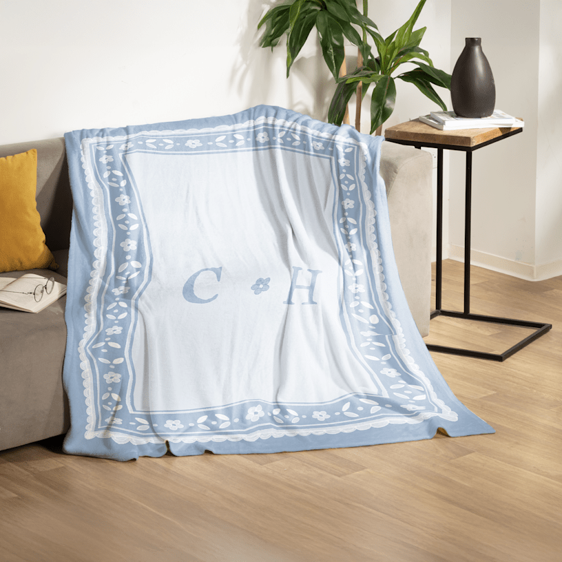 A custom monogrammed blanket draped over a living room couch. 