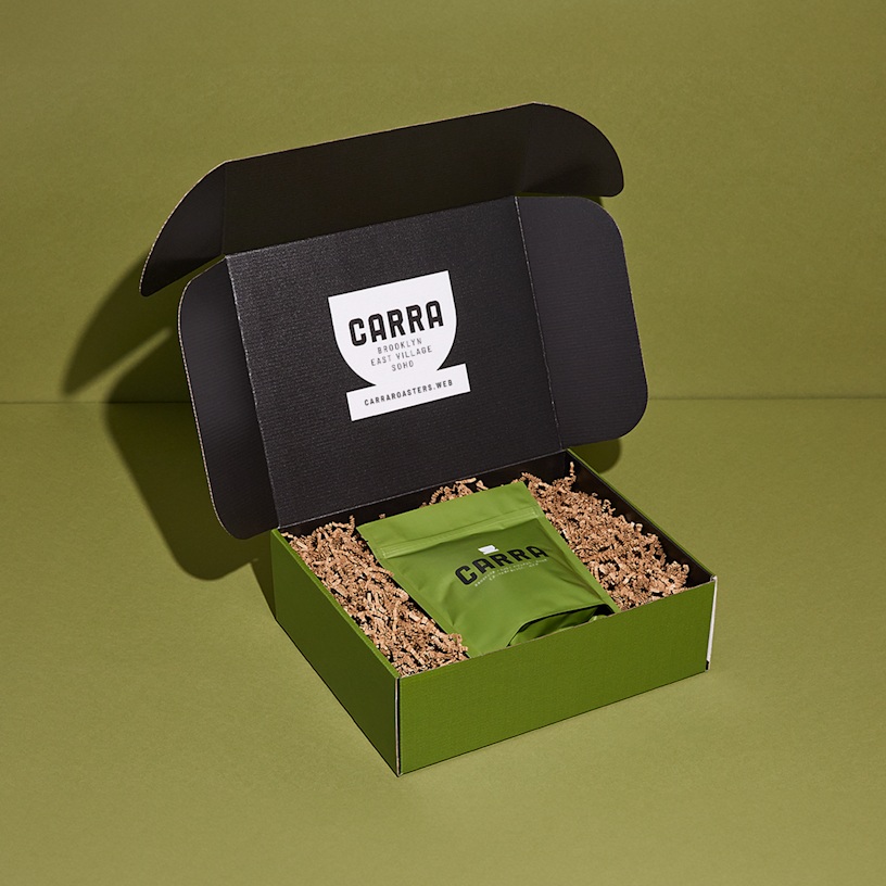 Una caja postal con impresión total, con papel triturado y una bolsa de café adentro. Los beneficios destacados incluyen: precios inigualables, tiempo de entrega líder, impresión vívida y envío gratis.