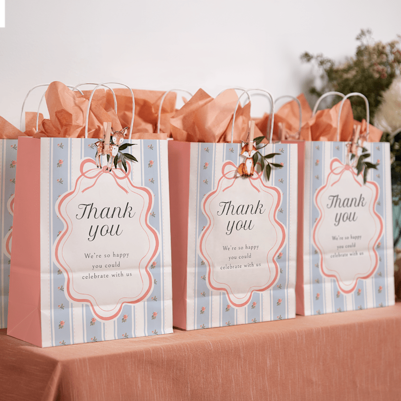 A table of brown party bags at a birthday, decorated with flowers and ribbon.