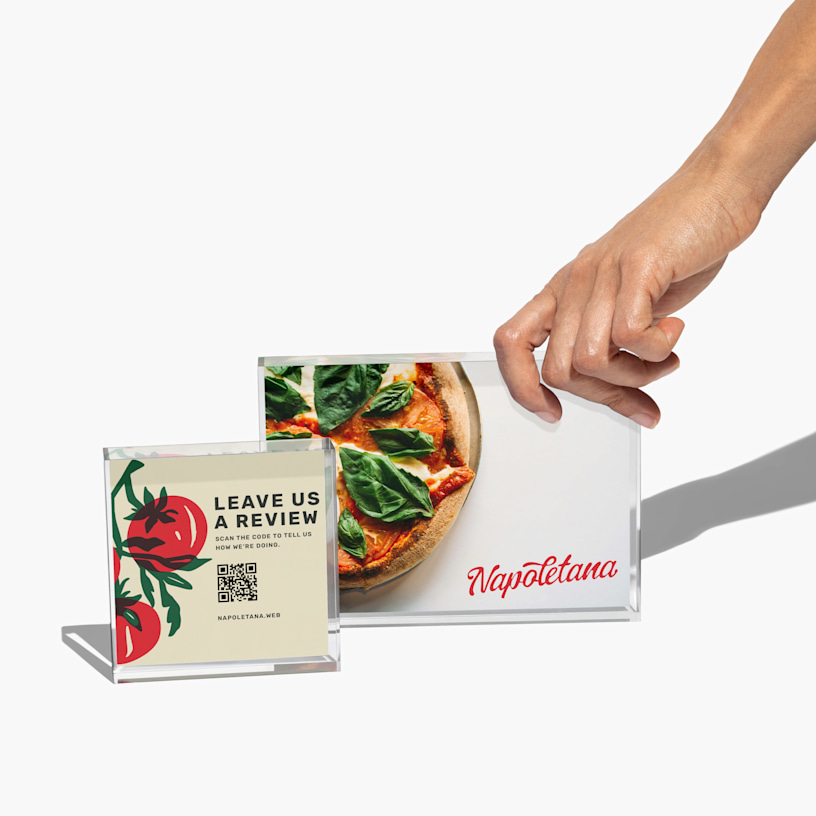 Dos soportes para carteles acrílicos transparentes que exhiben la imagen del menú de un restaurante italiano y un cartel de reseña con código QR.