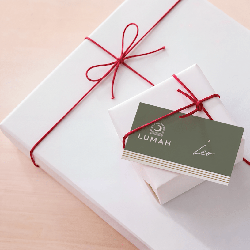 Una targhetta per regalo personalizzata con un design natalizio, infilata sotto il nastro di un regalo incartato. 