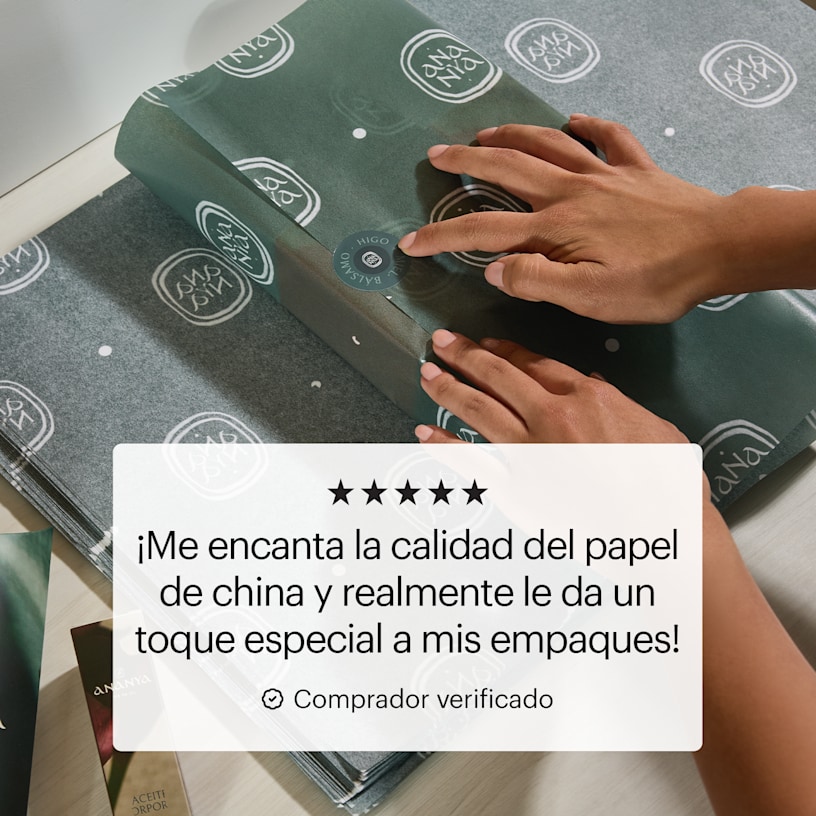 Un par de manos empacando una caja de regalo con papel de china con impresión personalizada, y la reseña de un cliente que dice: “Me encanta la calidad del papel de china porque le da un toque totalmente especial a mis empaques”.