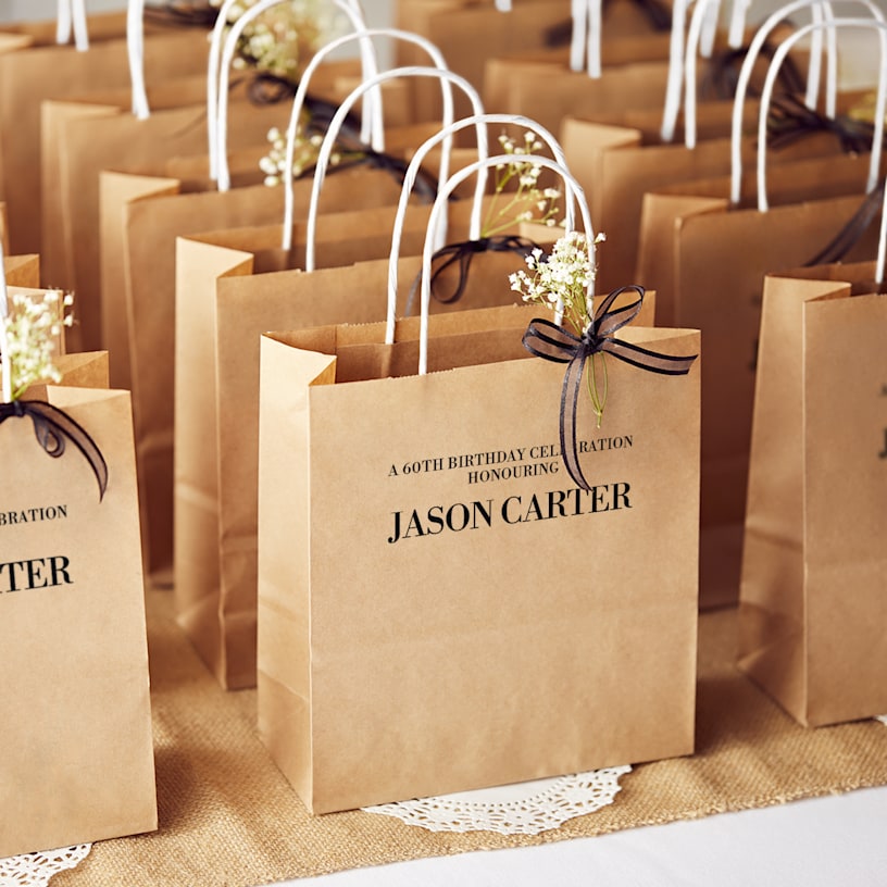 White paper bag with gold stars and text celebrating a 60th birthday.