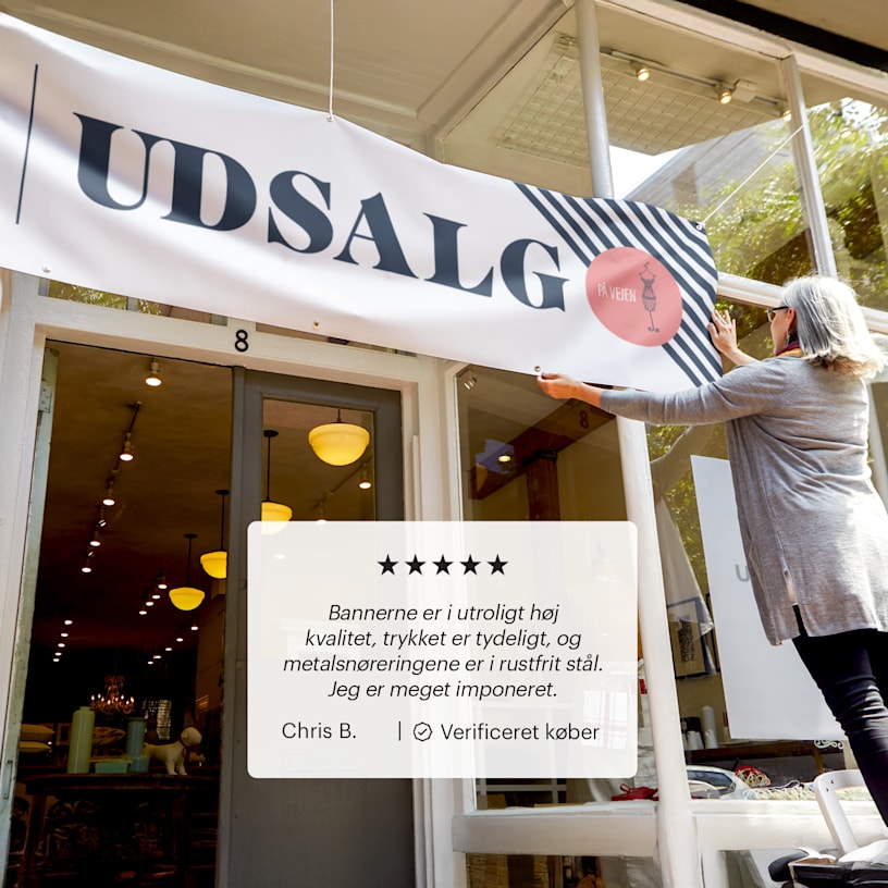 En virksomhedsejer hænger et vinylbanner op, der reklamerer for et salg og har en kundeanmeldelse: "De bannere, vi har købt, er fantastiske! De er tydelige, og farverne er flotte og klare. De er robuste, og udendørsbannerne holder godt i vejret."