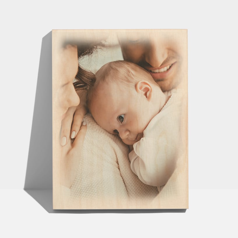 En fotoblok i træ med et foto af et par, der holder deres nyfødte baby. 