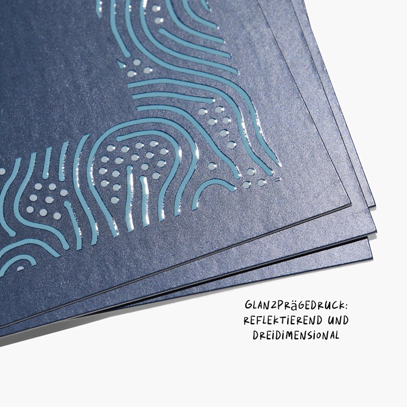 Eine Nahaufnahme von Visitenkarten mit Spotlack, deren Glanzprägedruck reflektierend und dreidimensional wirkt.