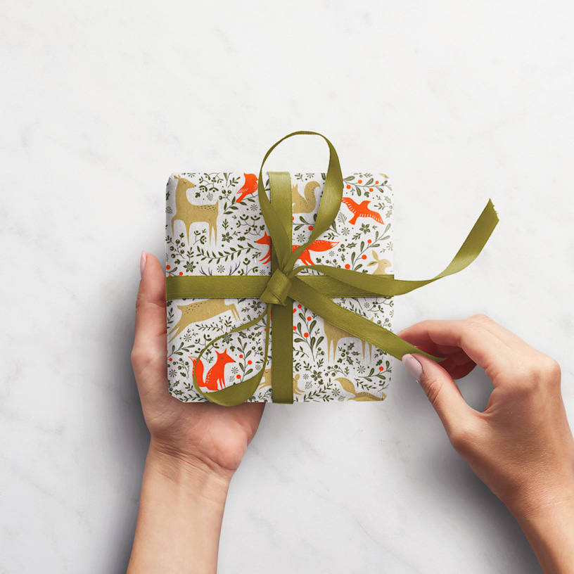 Kind übergibt Geschenk mit bedrucktem Geschenkpapier