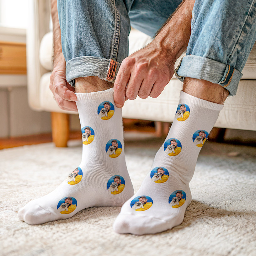 Zwei Füße in personalisierten Socken mit Fotos eines Pärchens. 