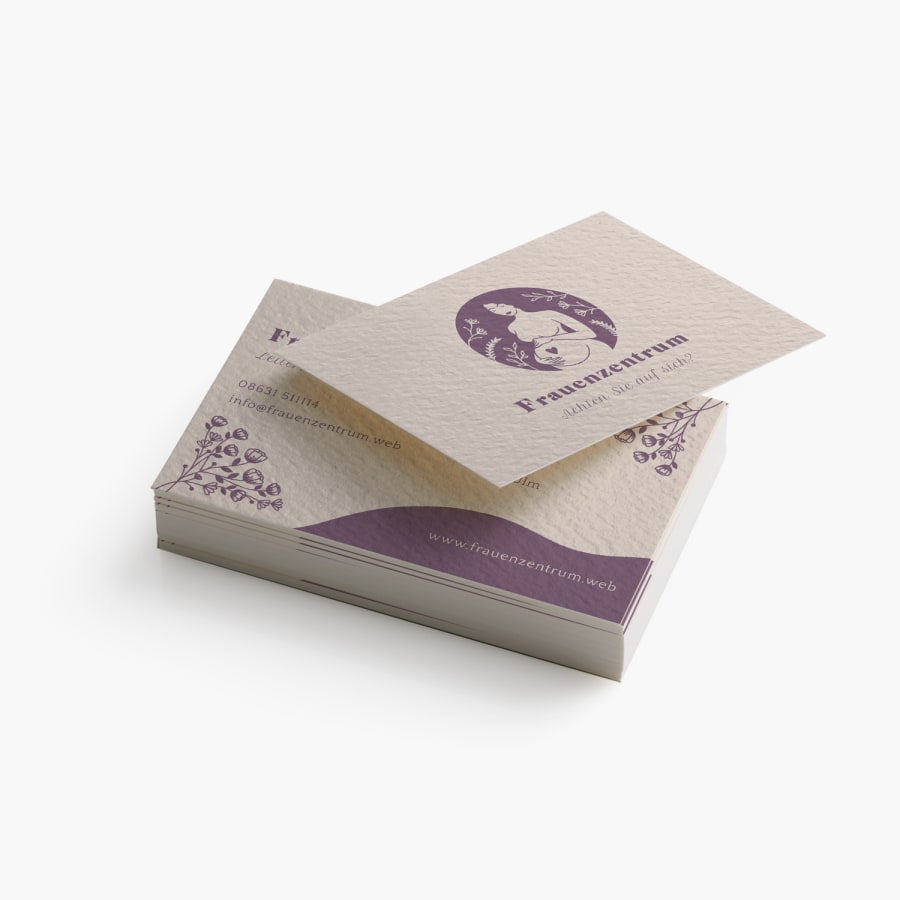 Ein Stapel Visitenkarten mit Strukturpapier, die auf Vorder- und Rückseite ein Frauengesundheitszentrum bewerben.