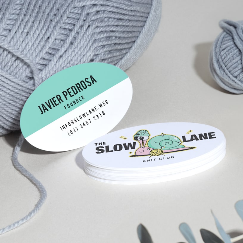 Oval business cards promoting a crochet business, displayed on a counter.