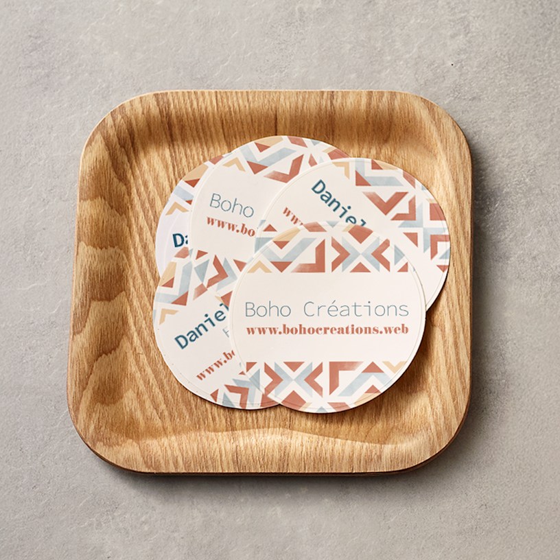 Patterned circle business cards promoting a craft business, displayed on a wooden dish. 