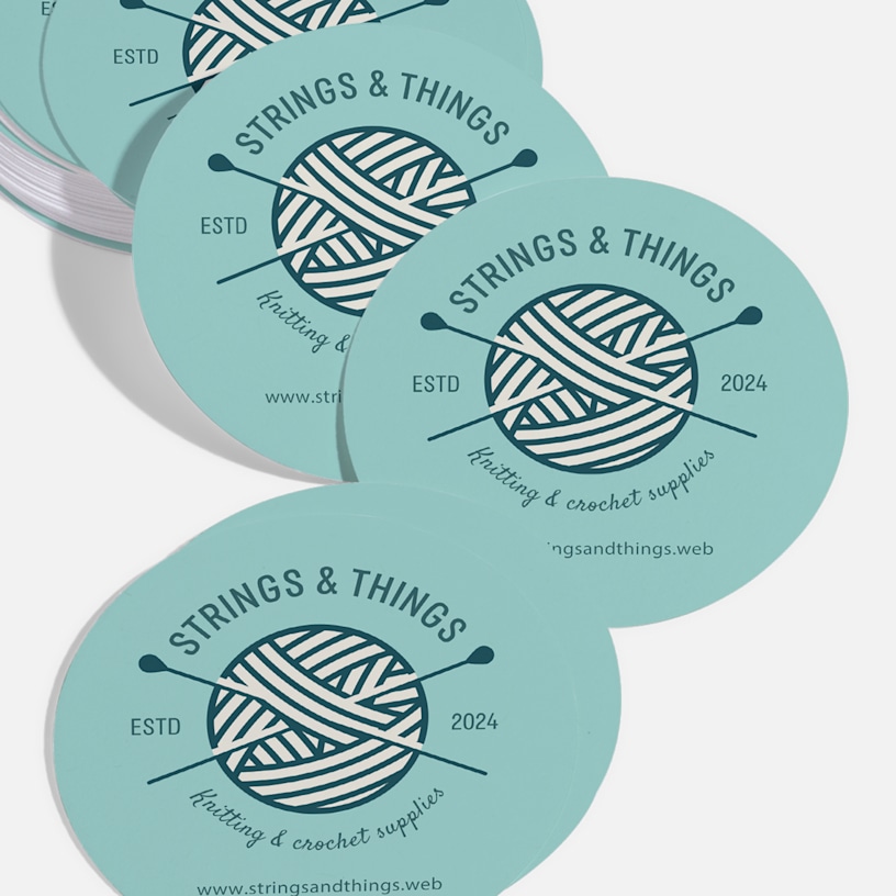 Circle business cards promoting a crochet business, displayed on a counter.