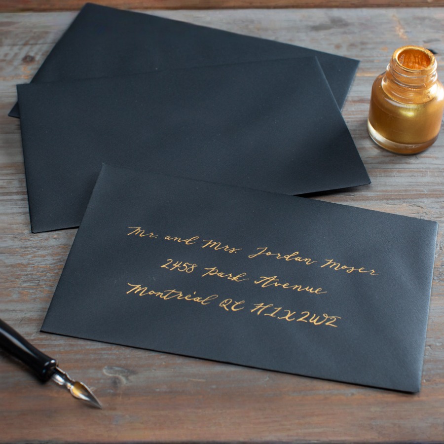 A black custom envelope addressed in gold-colored ink.