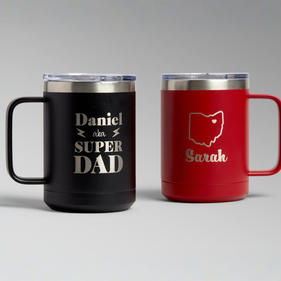 Two 15 oz. travel mugs, one black and one red, both laser etched with custom designs. 