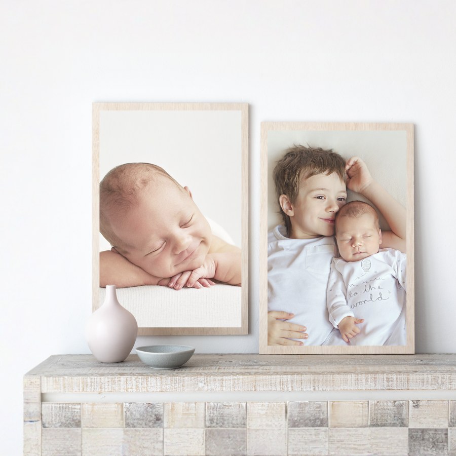 Two wood prints featuring photos of a baby and his brother, displayed on a tabletop. 