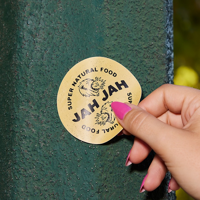 A person placing a circle sticker for a natural food business on an iron surface. 