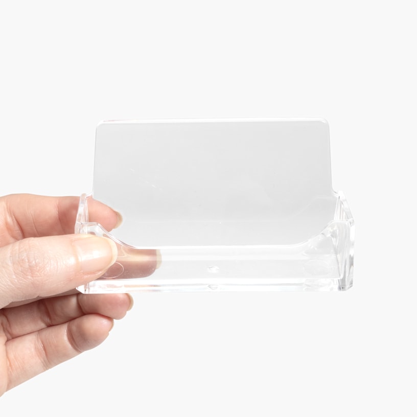An acrylic business card holder being held in someone’s hand.