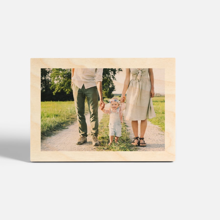A tabletop wood print featuring a photo of a couple walking hand in hand with their toddler. 