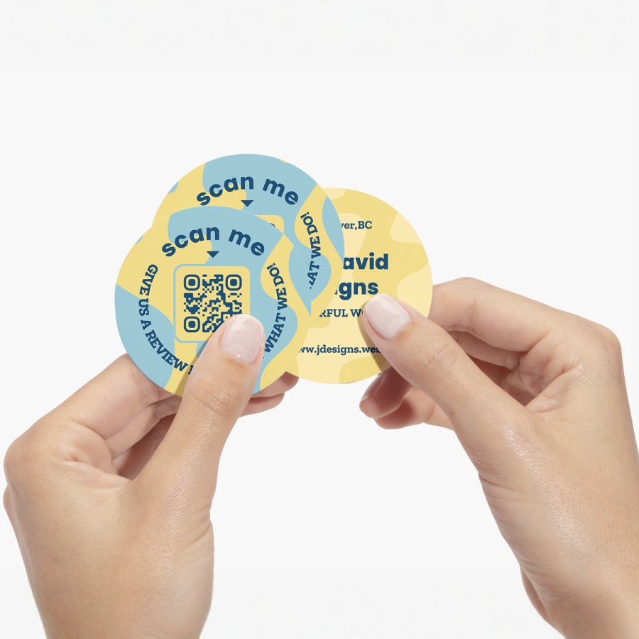  A person holding three circle business cards with QR codes in the design.