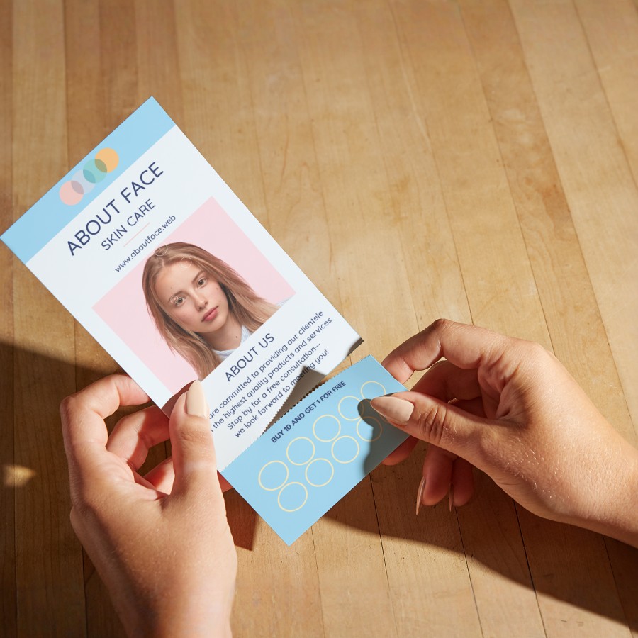A person detaching a loyalty card from a rip card for skincare services. 